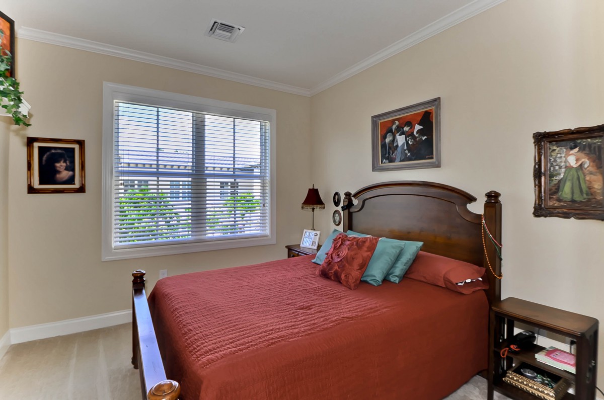 A cozy bedroom with a wooden bed frame, pillows, and a large window letting in natural light.
