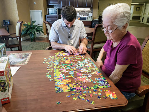 A young man and an elderly woman working together on a colorful jigsaw puzzle.