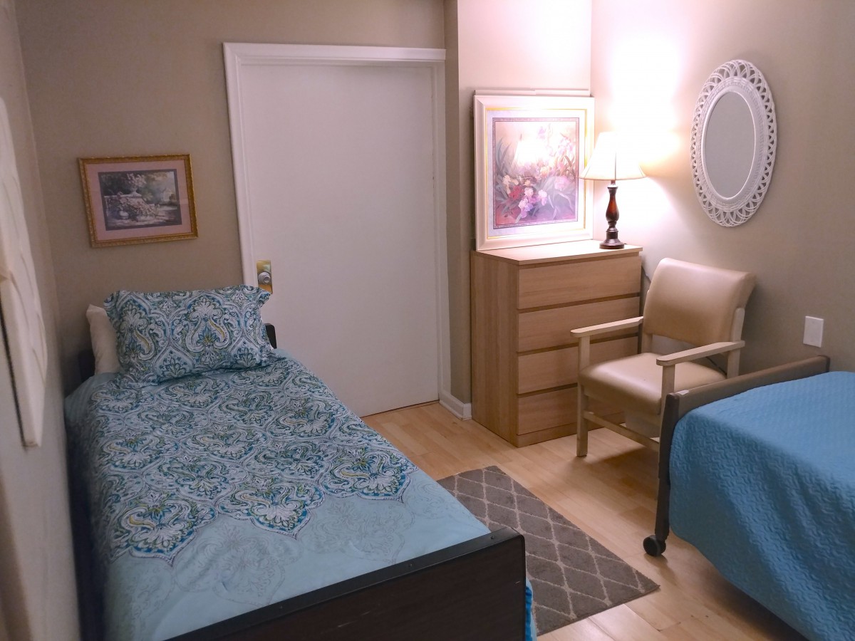 A cozy bedroom with a single bed, dresser, chair, and decorative artwork.