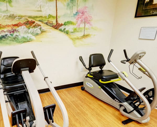 A small indoor gym area with exercise equipment including stationary bikes and a rowing machine.