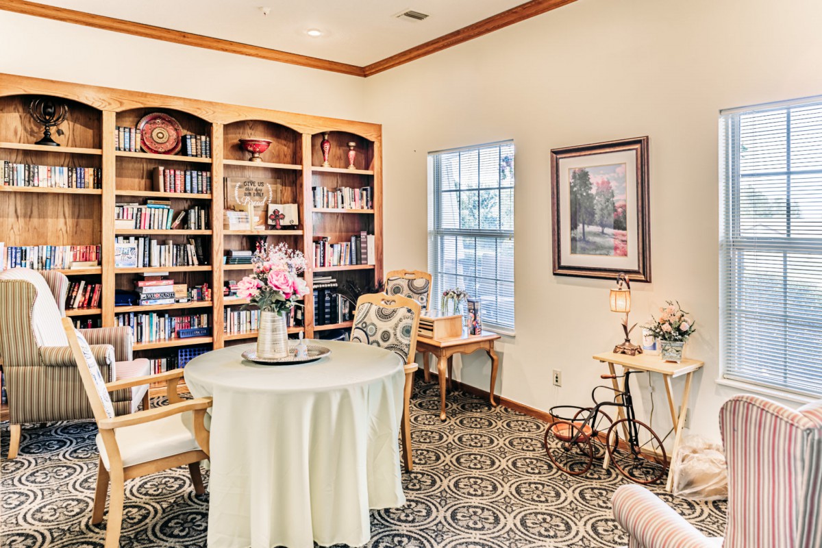 A cozy library with a round table and bookshelves filled with books.