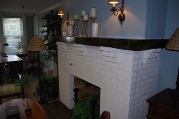 A cozy interior with a decorated fireplace mantel featuring candles and plants.