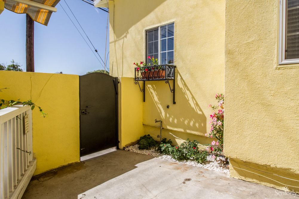 A sunny yellow house exterior with a small garden and decorative window box.