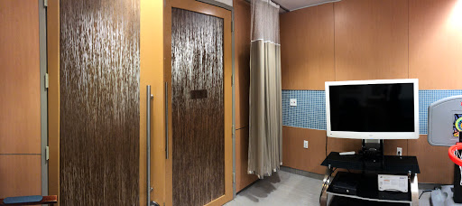 An interior view of a hospital room featuring a translucent door and a privacy curtain.