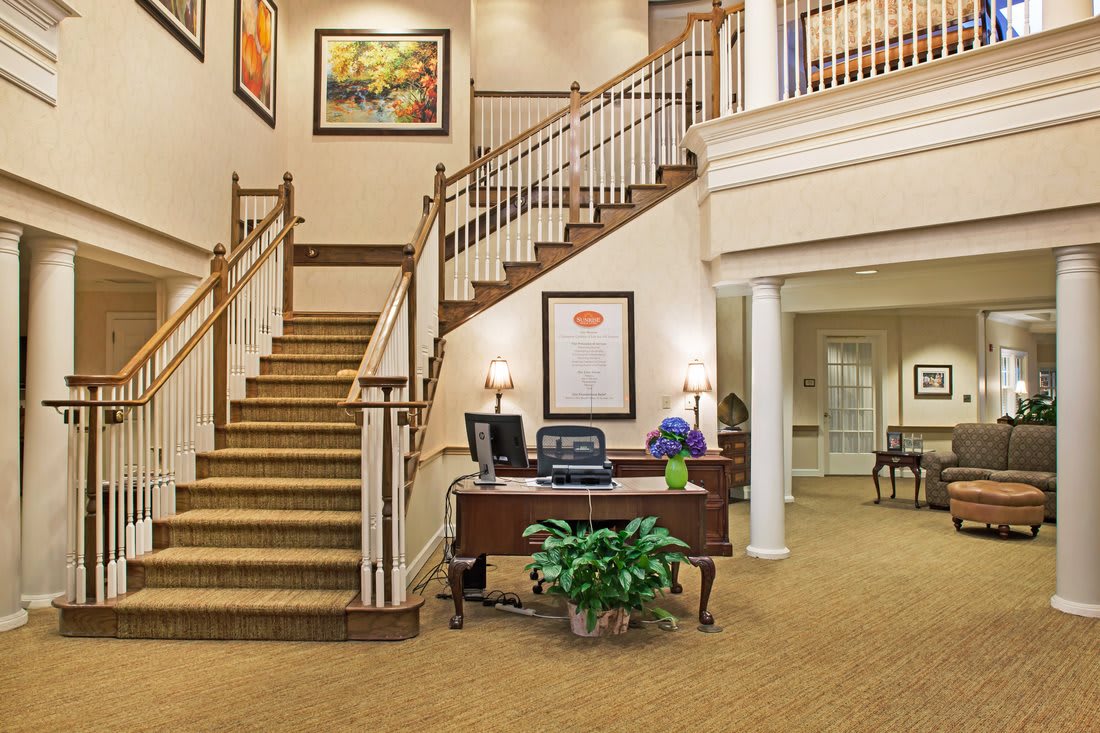 A welcoming lobby area with a reception desk, staircase, and decorative artwork.