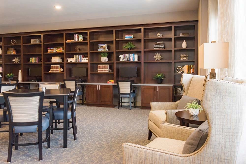 A cozy library setup with bookshelves, comfortable chairs, and a study table.