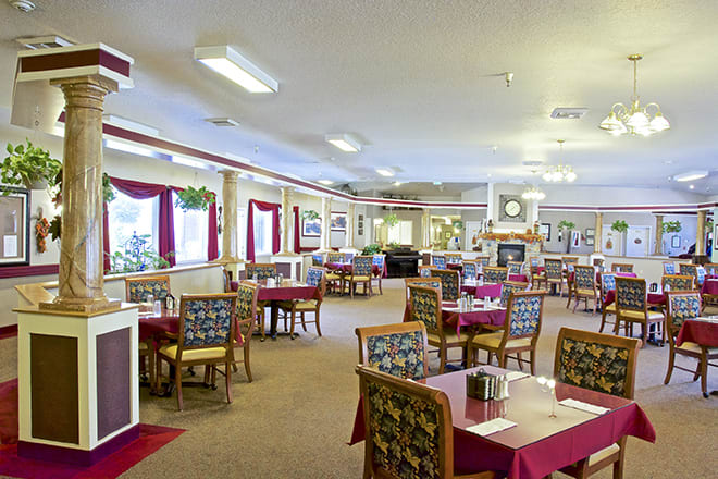 A spacious dining room with tables and chairs arranged neatly, featuring elegant decor and soft lighting.