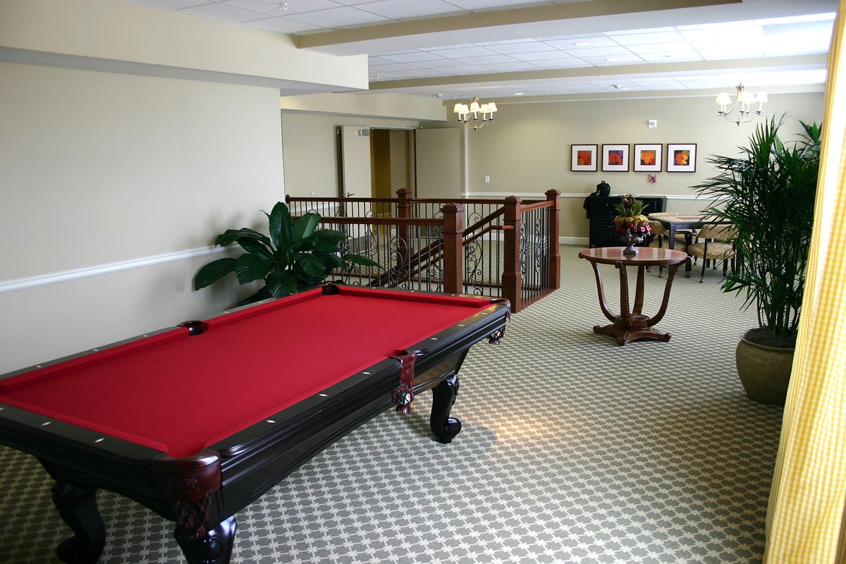 A spacious game room featuring a billiard table with red felt, comfortable seating, and stylish decor.