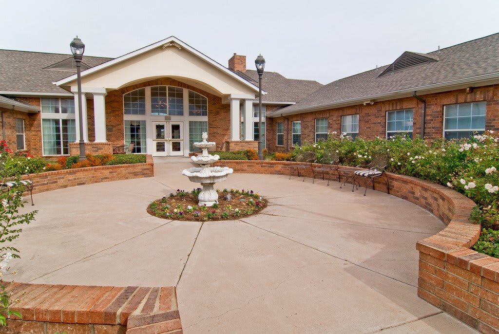 A brick building with a central entrance and a decorative fountain in the foreground.