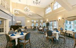 A spacious dining room with tables set and ambient lighting, featuring large windows and elegant chandeliers.