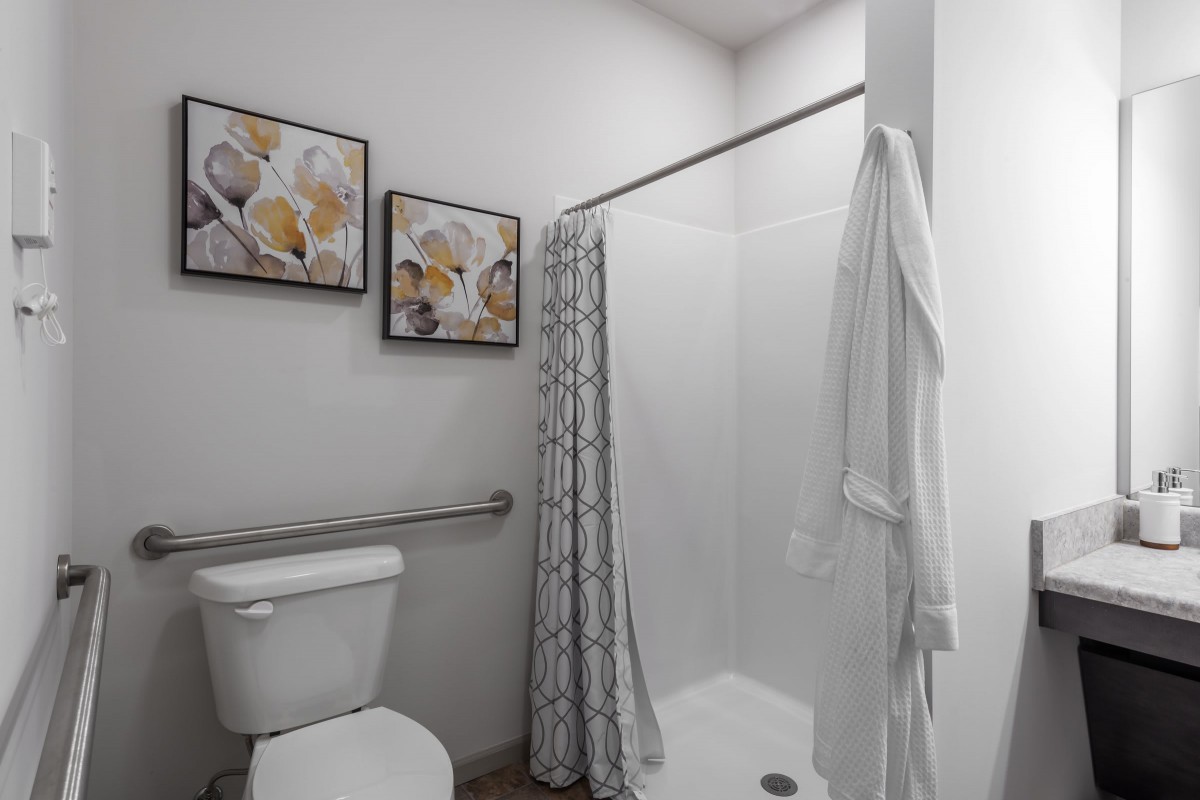 A clean and modern bathroom with decorative artwork and a white shower curtain.