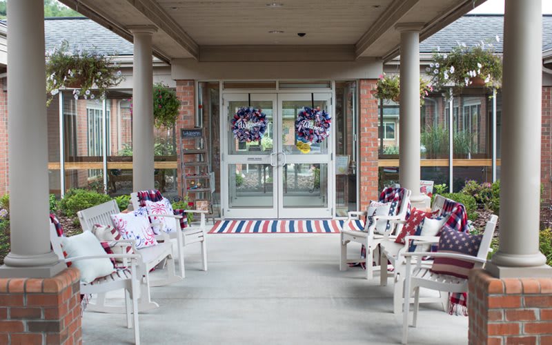 An entrance decorated with patriotic wreaths and chairs adorned with themed pillows.
