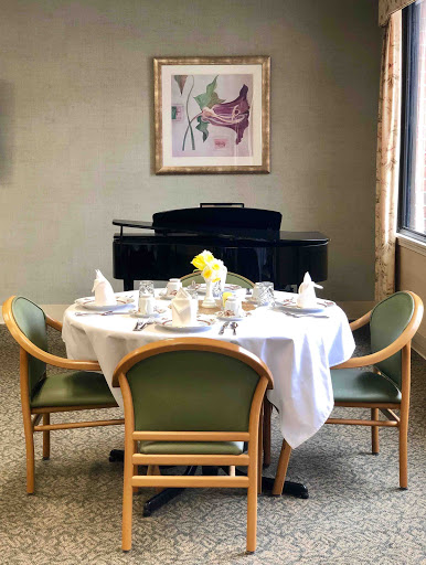 An elegantly set dining table with a piano and artwork in the background.