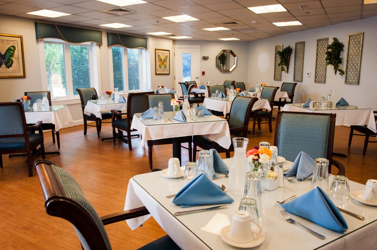 A cozy dining room with neatly set tables featuring blue napkins and a welcoming ambiance.