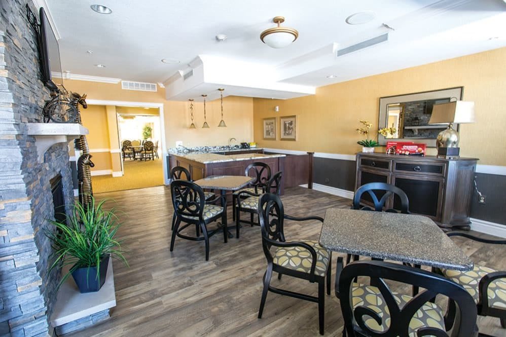 A modern dining area with tables and chairs, accented by ceiling lights and indoor plants.
