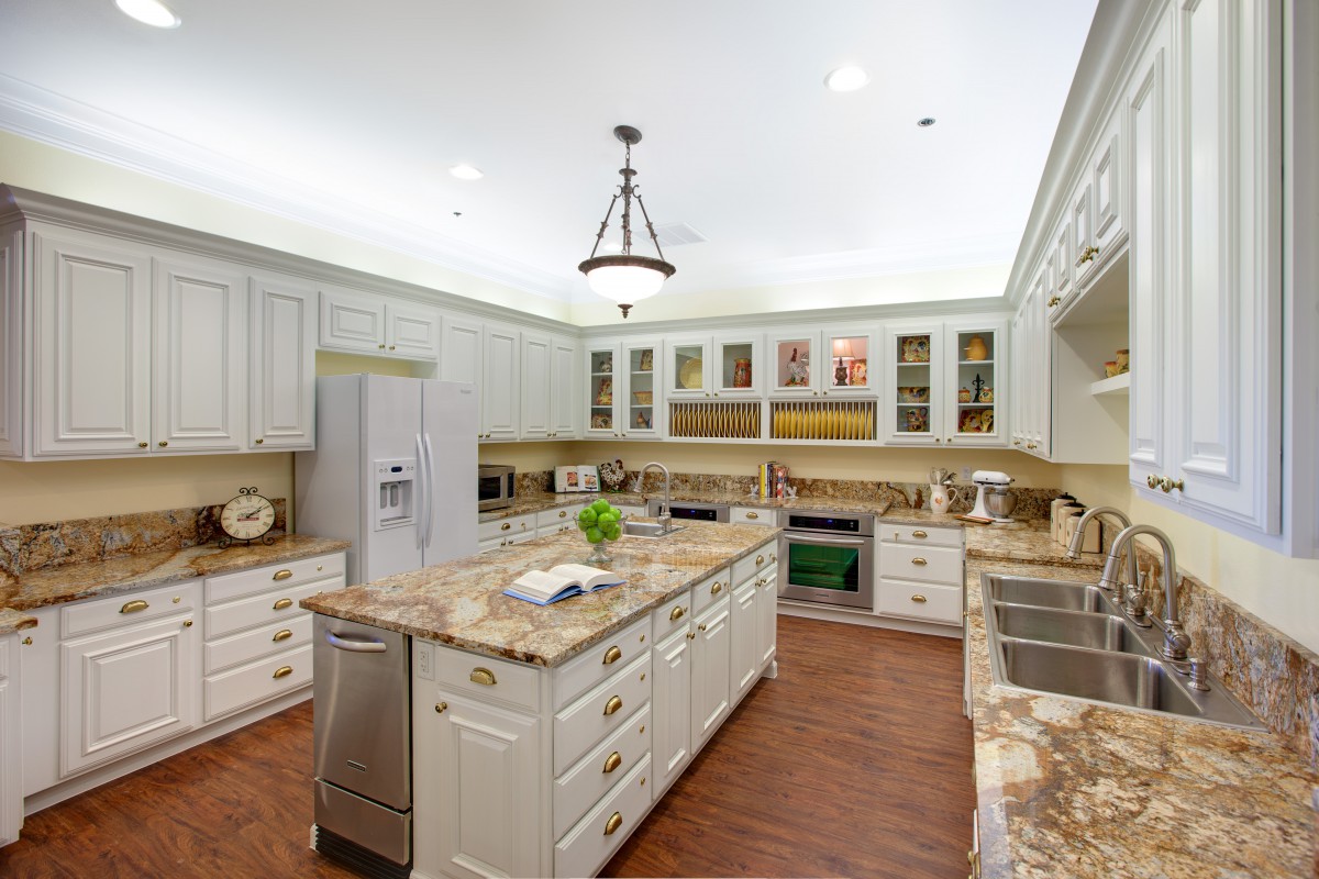 A spacious, modern kitchen with a central island and marble countertops.