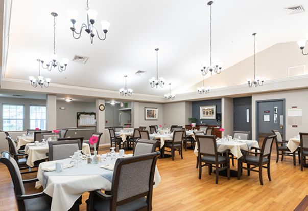 A spacious and elegantly designed dining area with multiple tables and modern chandeliers overhead.