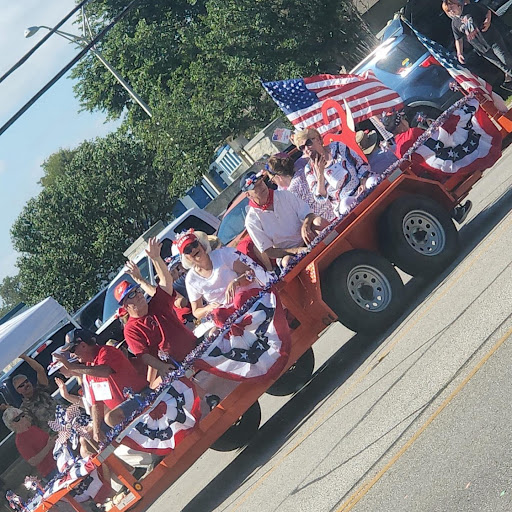 A festive parade scene showcasing a decorated float with participants celebrating with American flags.