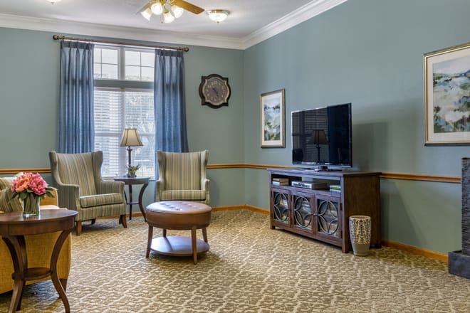 A cozy living room with two chairs, a coffee table, and a TV on an entertainment unit.