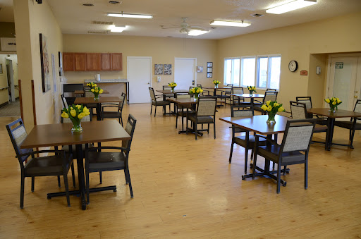 A well-lit dining area featuring several tables with flower centerpieces.
