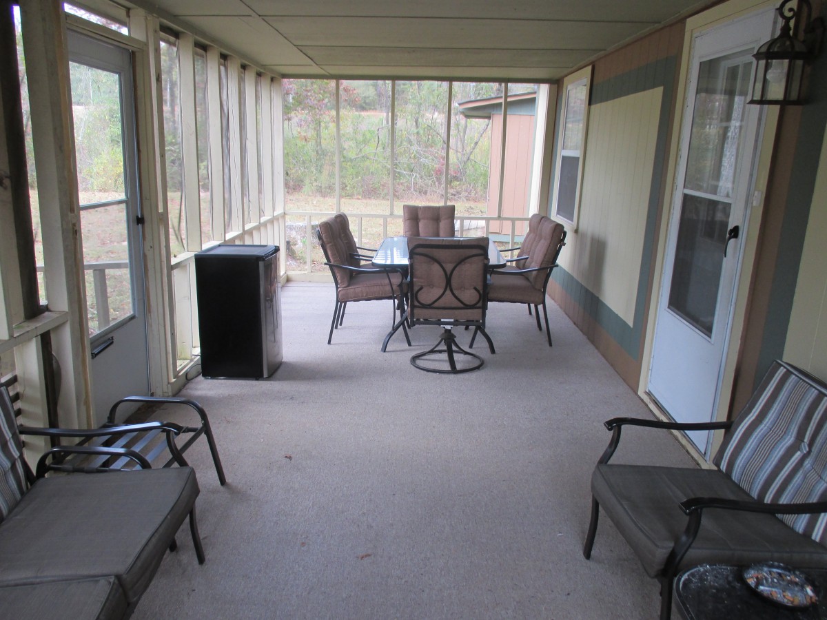 A cozy screened porch featuring a table and chair seating area.