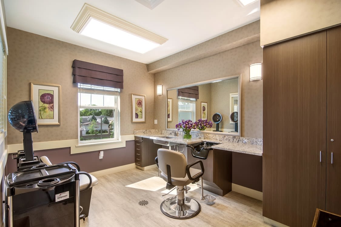 A modern salon interior with a large mirror, comfortable chair, and stylish lighting.