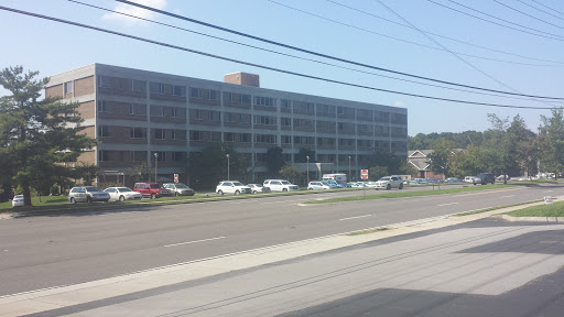 A view of a multi-story building with parked cars in front.