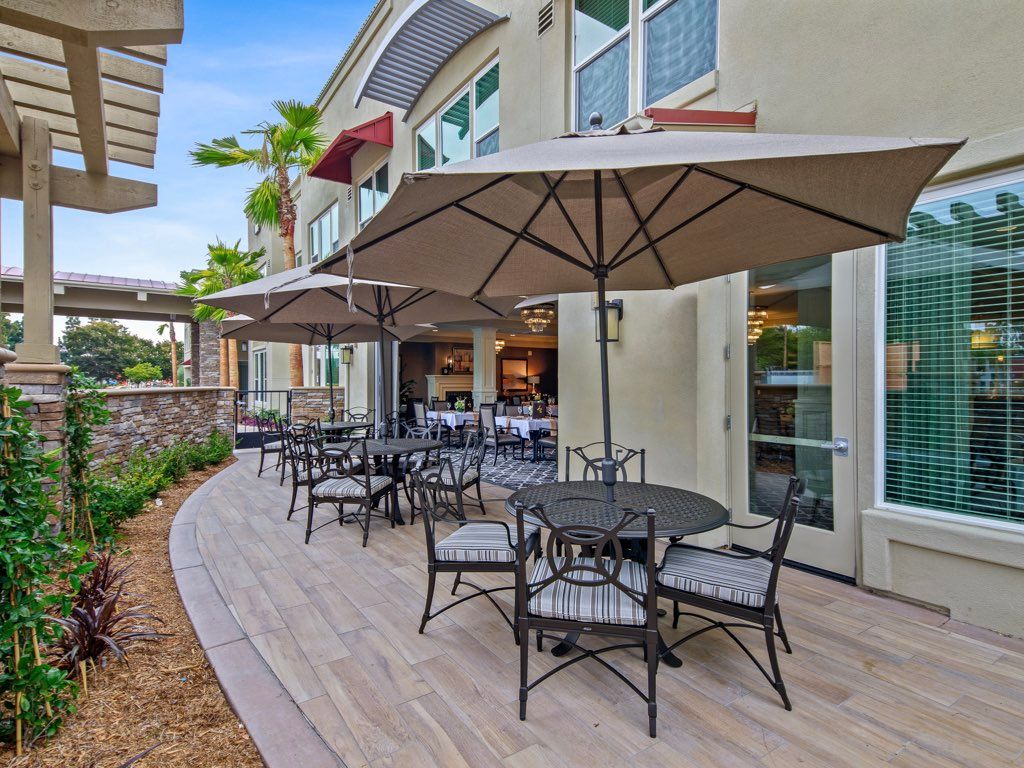 An outdoor patio area with tables, chairs, and umbrellas set up for dining.