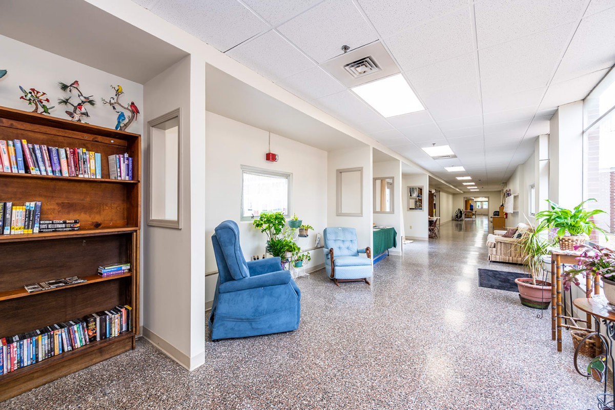 A bright and spacious hallway with comfortable seating and a bookshelf.