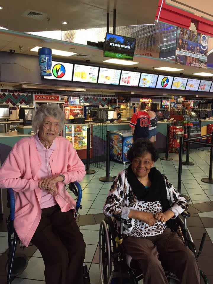 Two individuals in wheelchairs at a cinema concession stand.