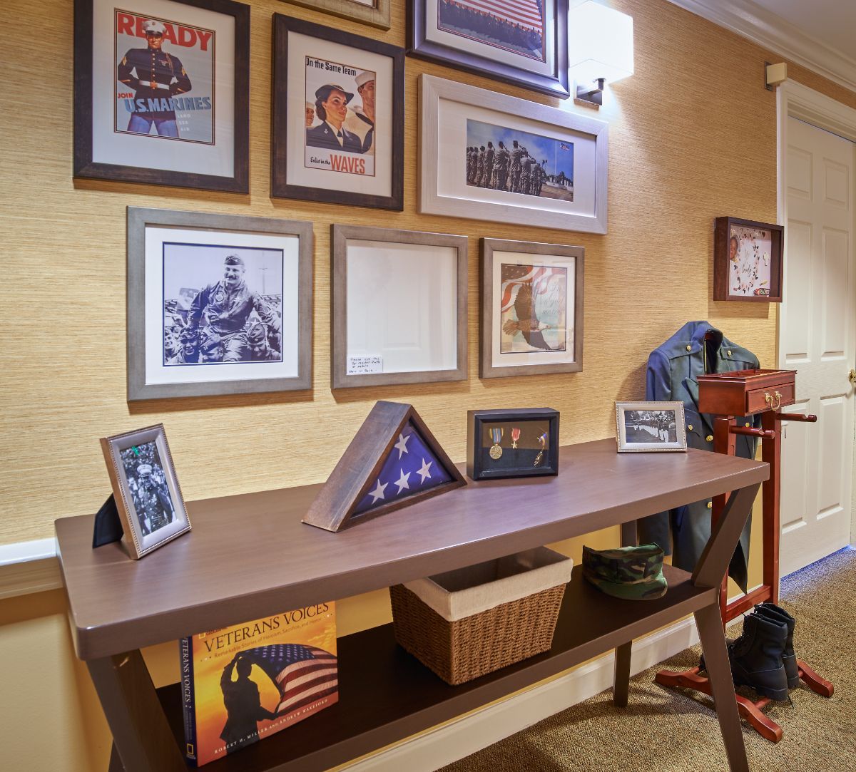 A home interior featuring a console table adorned with military memorabilia and a wall decorated with framed photos.