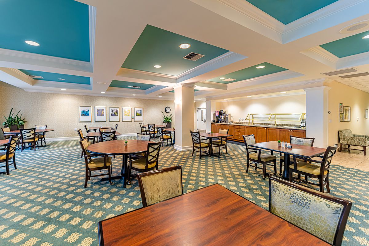 A spacious dining area with neatly arranged tables and chairs, featuring a buffet counter along one wall.