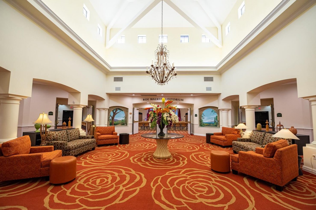 A spacious and elegantly decorated lobby featuring comfortable sofas, a chandelier, and patterned carpet.