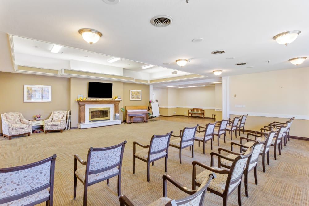An empty conference room with chairs arranged in rows, featuring a television and a fireplace.