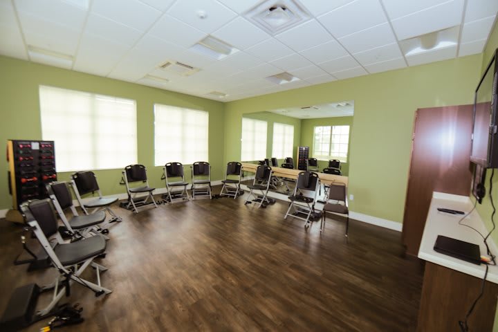 An empty, well-lit meeting room with chairs arranged in a circle and wooden flooring.
