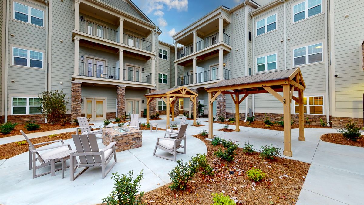 A modern apartment complex featuring an outdoor seating area with pergolas and well-maintained landscaping.