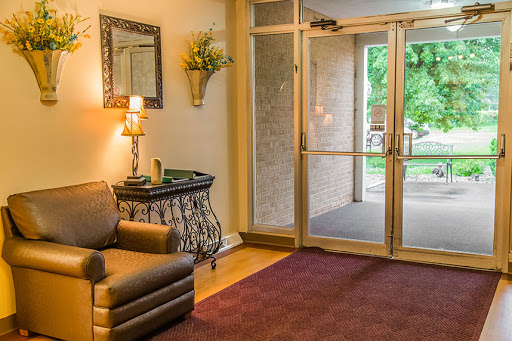 A cozy lobby area featuring comfortable seating, a stylish lamp, and an inviting entrance.