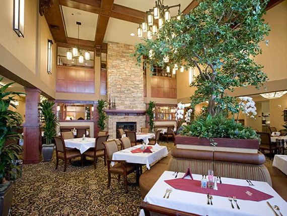 An elegant restaurant interior featuring a cozy dining area with a central fireplace and decorative chandeliers.