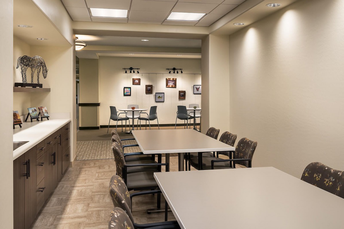 A well-lit conference room with multiple tables and chairs, suitable for meetings or collaborative work.