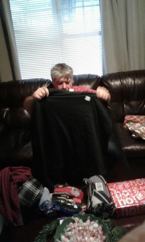 A person holding up a piece of clothing while sitting on a sofa.