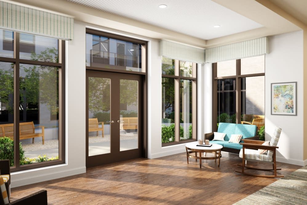 A modern living room with large windows allowing natural light to fill the space, featuring wood flooring and stylish furniture.