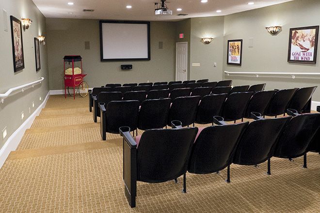 An empty theater room with rows of seats facing a projection screen.