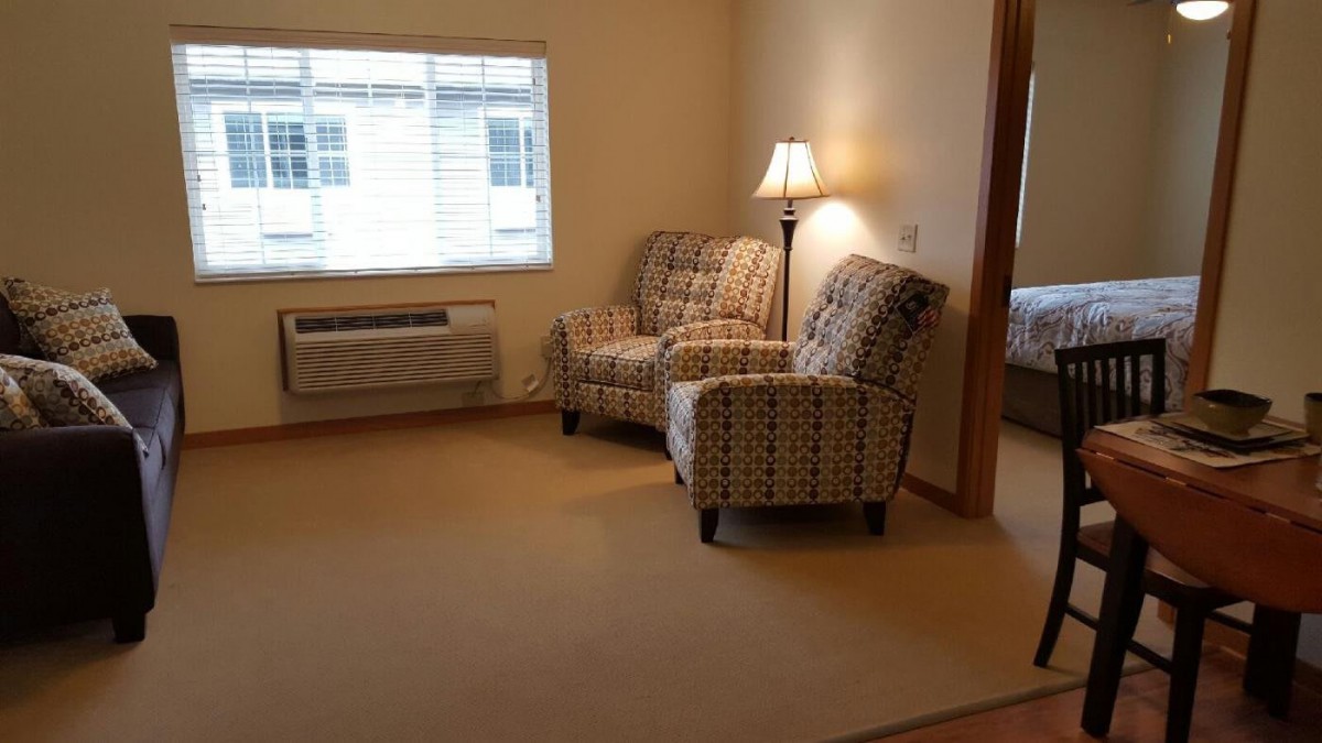 A cozy living room with armchairs, a lamp, and a window.