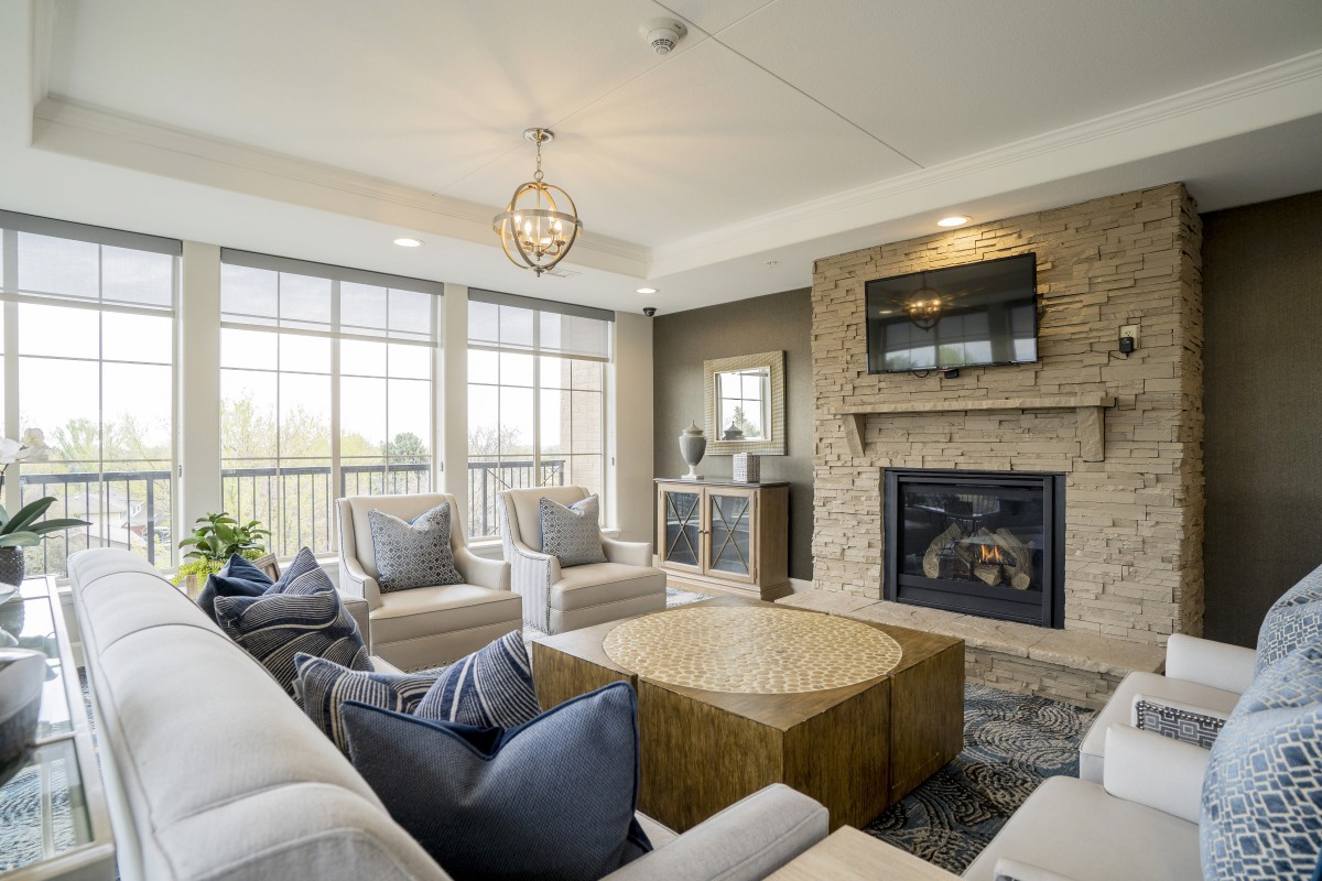 A modern living room with a large window, fireplace, and stylish furniture.