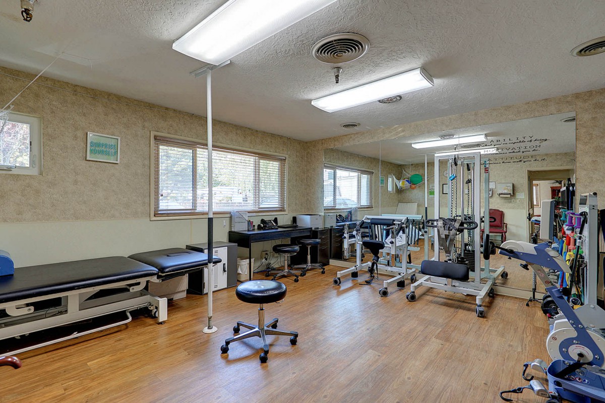 A well-equipped physical therapy room with exercise machines and treatment tables.