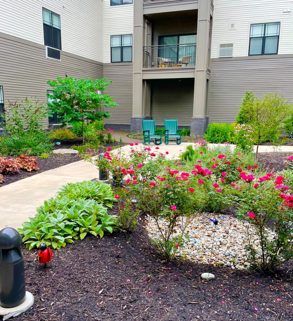 A beautifully landscaped garden with a variety of flowers and plants in front of an apartment building.