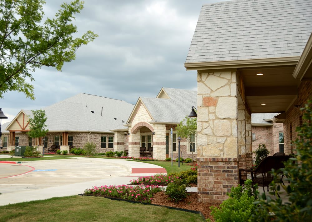 A residential building with a landscaped driveway under a cloudy sky.