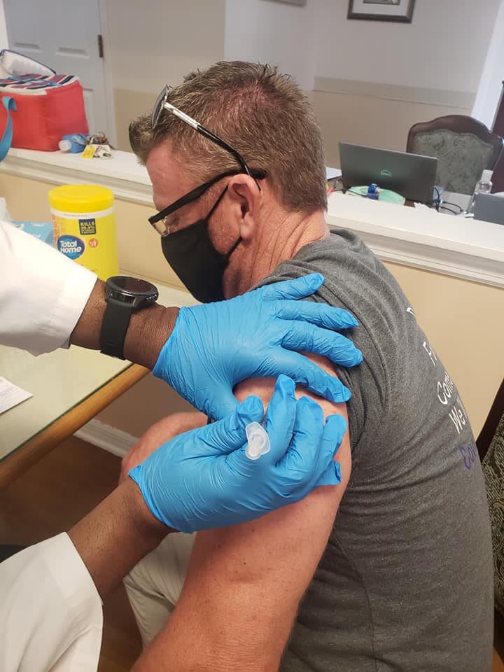 A person receiving a vaccine shot from a healthcare professional wearing gloves.