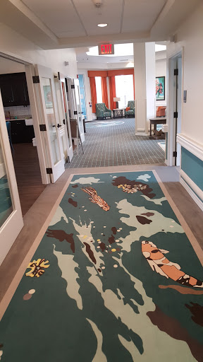 A vibrant hallway featuring a decorative rug with colorful patterns, leading to a sitting area.
