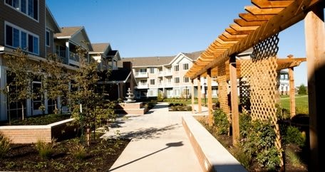 A residential complex with a landscaped garden and a pathway under a pergola.